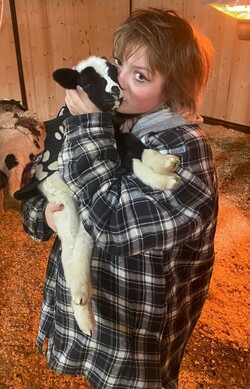 Teenage girl in barn holding new lamb