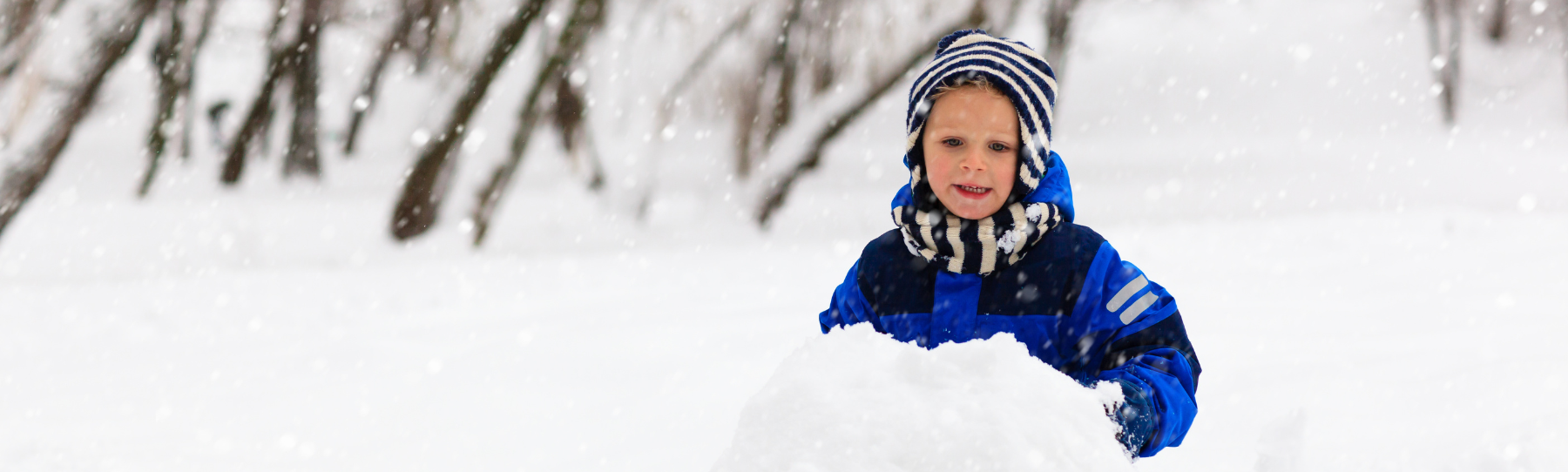 Child in snow rolling bottom ball for a snowman